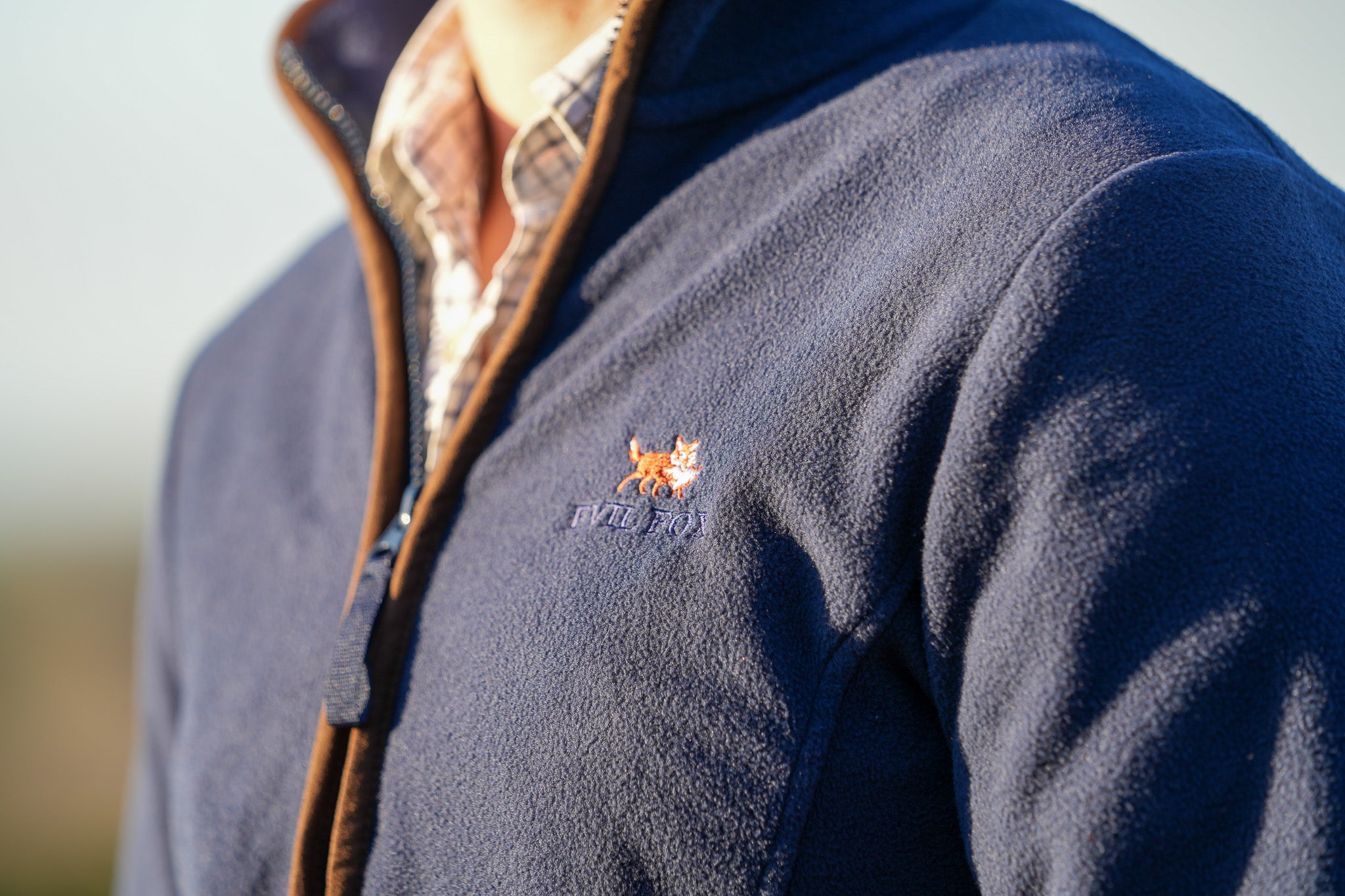 Navy fleece jacket with the evil fox logo on a blurred background