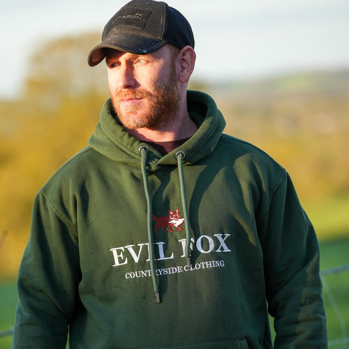Man wearing a green hoodie with 'Evil Fox' branding in an outdoor setting