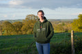 Person wearing a green hoodie with 'Evil Fox' logo standing in a field with trees and mountains in the background.